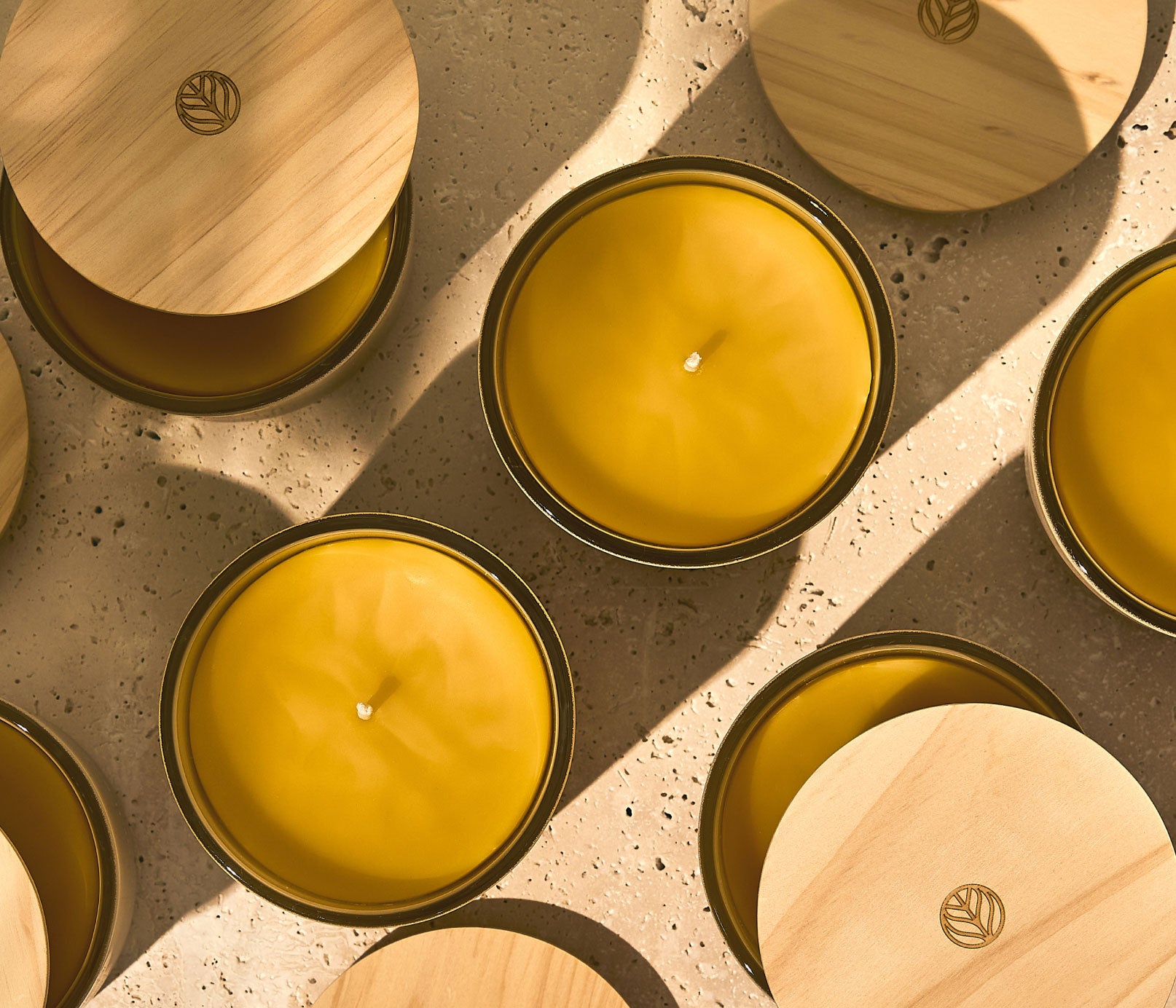 Multiple Branch Basics 100% Beeswax Candles, arranged in a grid with all candles featuring a wooden lid except for the two focal candles, which showcase the candle's beeswax. - View 4
